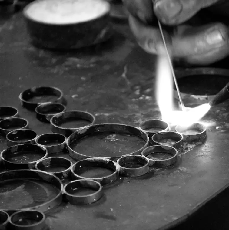 A craftsperson soldering metal rings by hand as part of KOKET's production process.