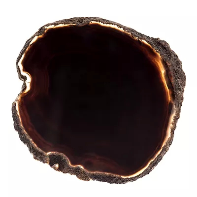 A close-up of a dark, almost black agate slice with subtle banding and a raw, natural edge, showcasing Koket's Black Agate finish.