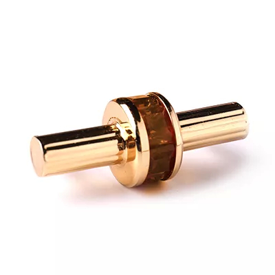 A close-up of a decorative handle with an amber-toned stone set in gold-toned metal, showcasing Koket's Exotica Handle Ambar.