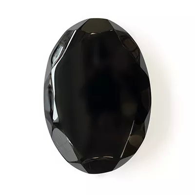 Close-up Gem Black: a faceted black gemstone with an intense shine and sharp reflections, on a white background.