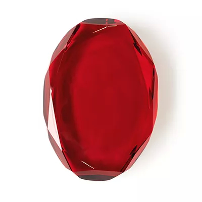 Close-up Gem Red: a faceted red gemstone with an intense shine and sharp reflections, on a white background.