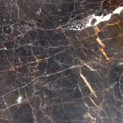 Close-up Port Laurent Marble: dark black marble with striking and irregular golden and white veins, featuring a polished and glossy surface.
