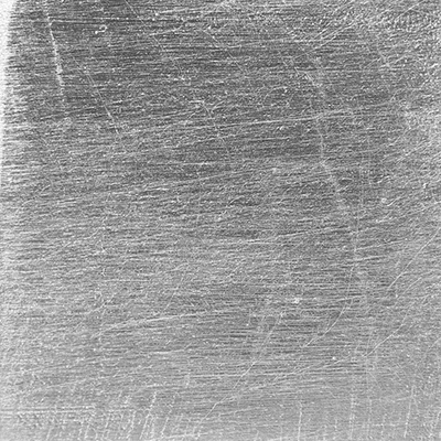 Close-up Silver Leaf: silver metallic surface with fine irregular brushing lines, featuring a soft sheen.