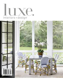 Luxe Interiors + Design magazine cover featuring an outdoor dining area with a glass table and patterned chairs.