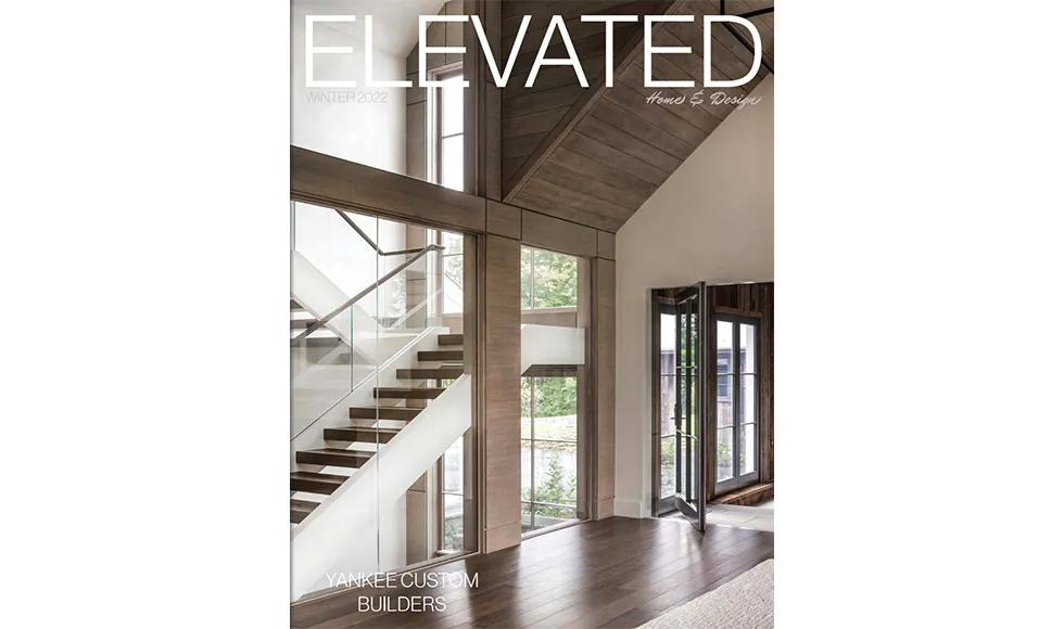 Elevated magazine cover showcasing a modern home interior with a grand staircase and large windows, by Yankee Custom Builders.