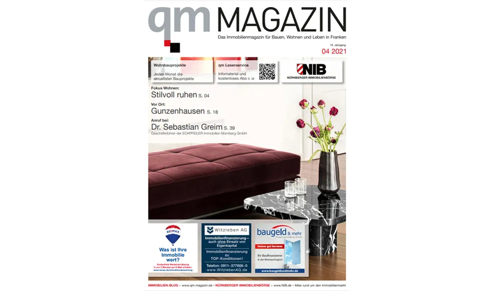 Cover of QM Magazin showing a modern living room scene with a burgundy sofa and a marble coffee table.