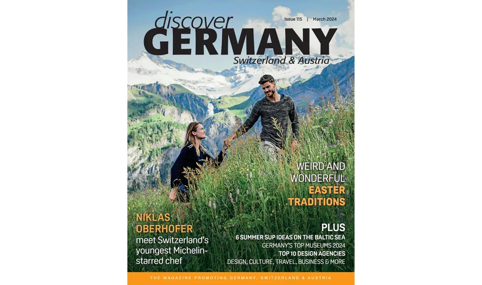 Cover of Discover Germany, March 2024, featuring a couple in a mountain field with Weird and Wonderful Easter Traditions.