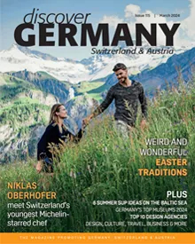 Cover of Discover Germany, March 2024, featuring a couple in a mountain field with Weird and Wonderful Easter Traditions.