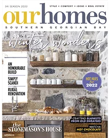 Our Homes magazine cover with Winter Wonders headline, featuring a rustic kitchen with stone wall and wooden shelves.