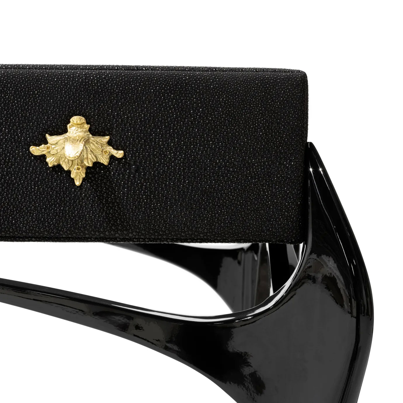 Elegant close-up detail of a decorative golden star-shaped handle on a black drawer of the Temptation Console, also showing the textured black surface of the drawer and the glossy black curved leg of the console.