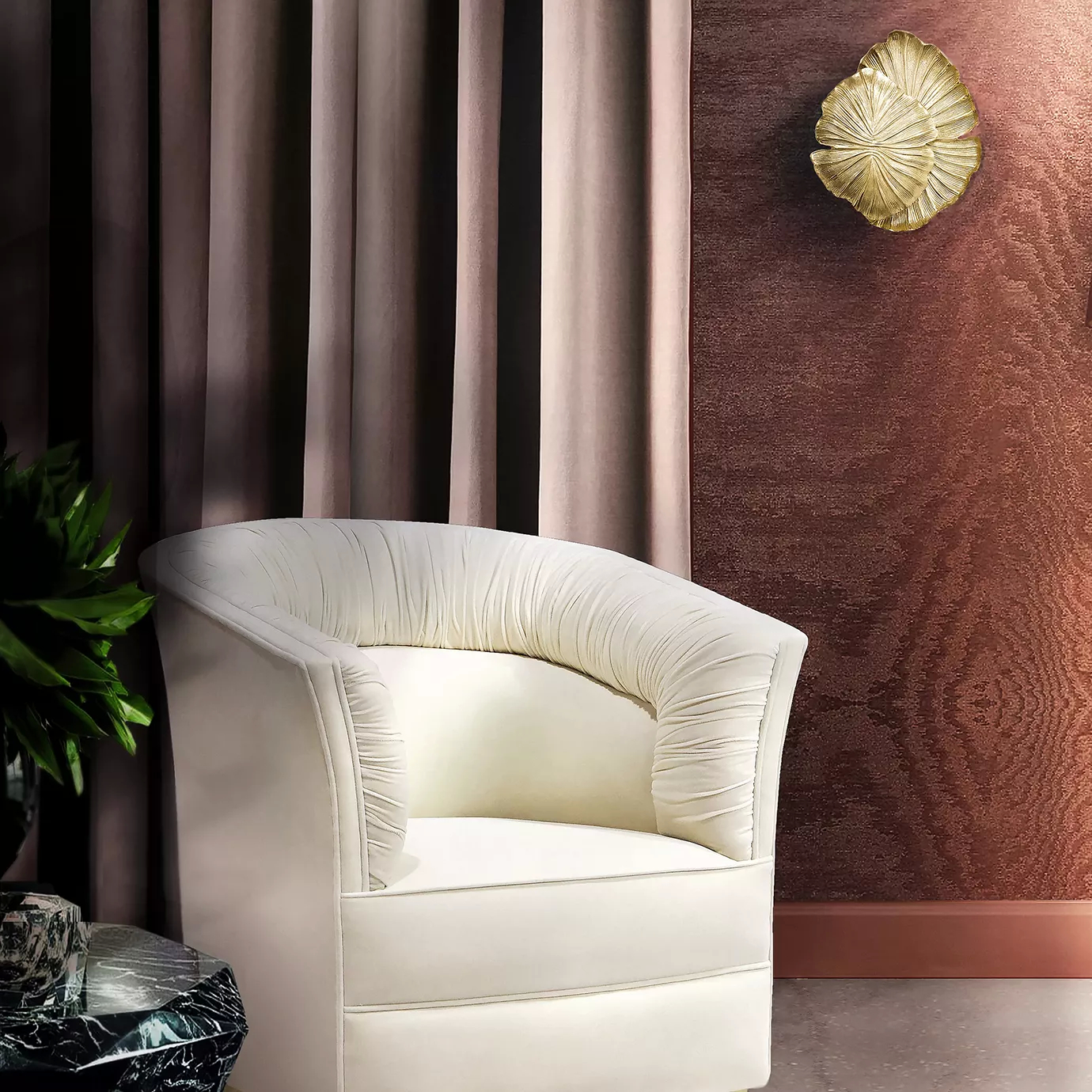 A cream armchair sits in a room with a brown wall and a bronze Passion Sconce, a plant, and a table.