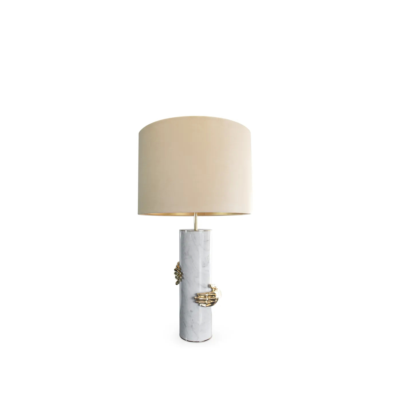 A Vengeance Table Lamp by Koket, featuring a white marble base with golden hands gripping it, and a light-colored drum shade.