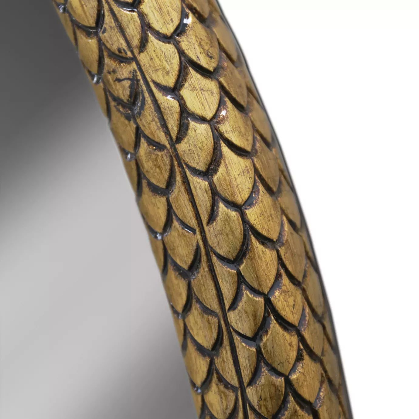 A detailed close-up of the Serpentine Apple Shaped Mirror reveals the exquisite golden scales of its snake frame.
