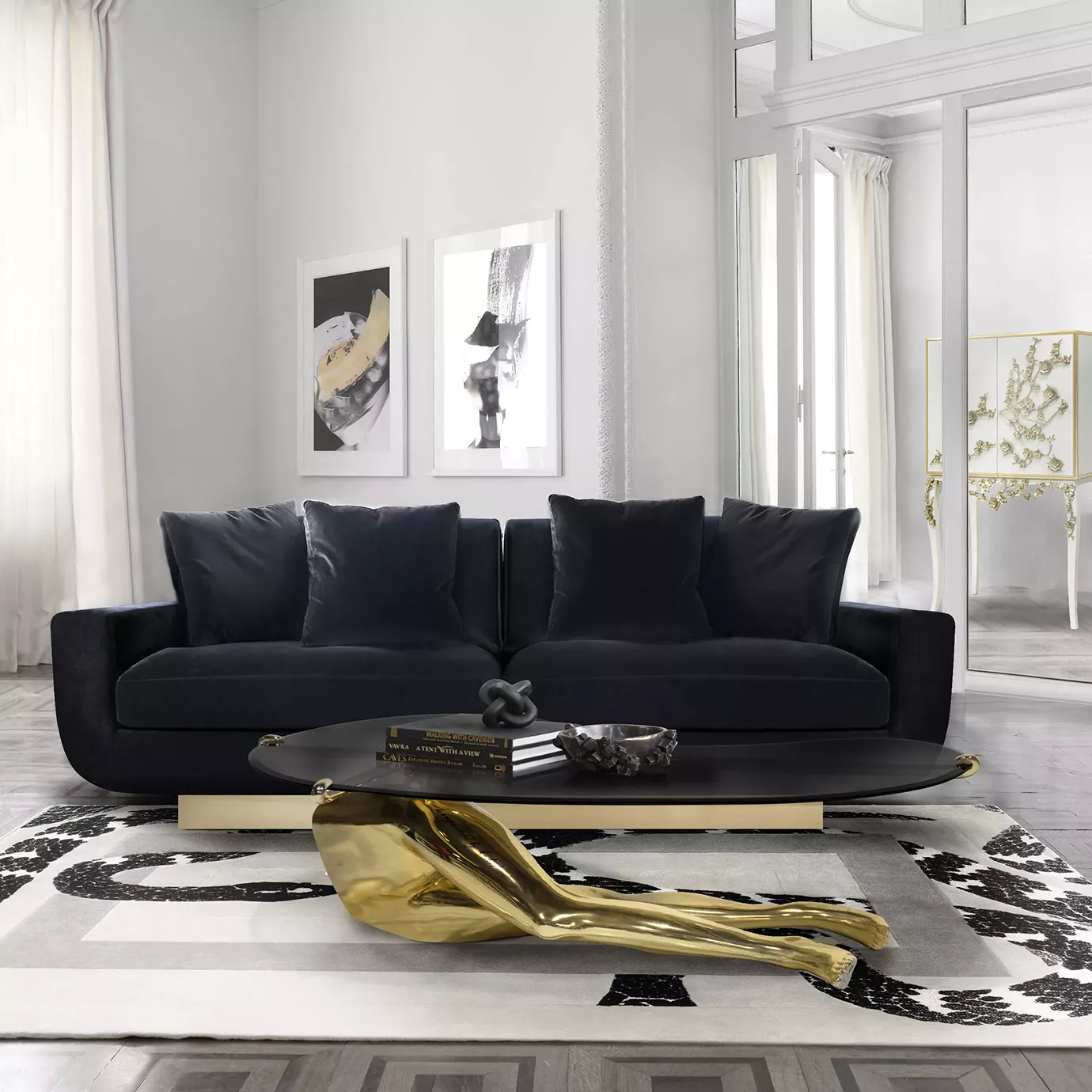 A luxurious Sofia Sofa in deep blue velvet with a gold base anchors a stylish living room with a unique coffee table and black and white rug.
