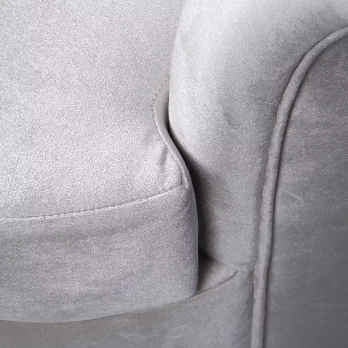Elegant close-up of the armrest and the white fabric upholstery with pleated details of the Besame Sofa.