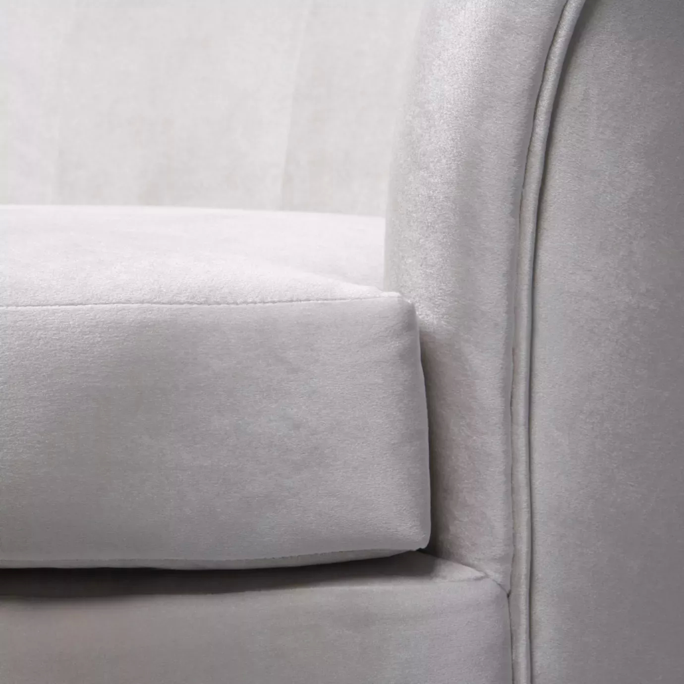 Elegant close-up of the armrest and the white fabric upholstery with pleated details of the Besame Sofa.