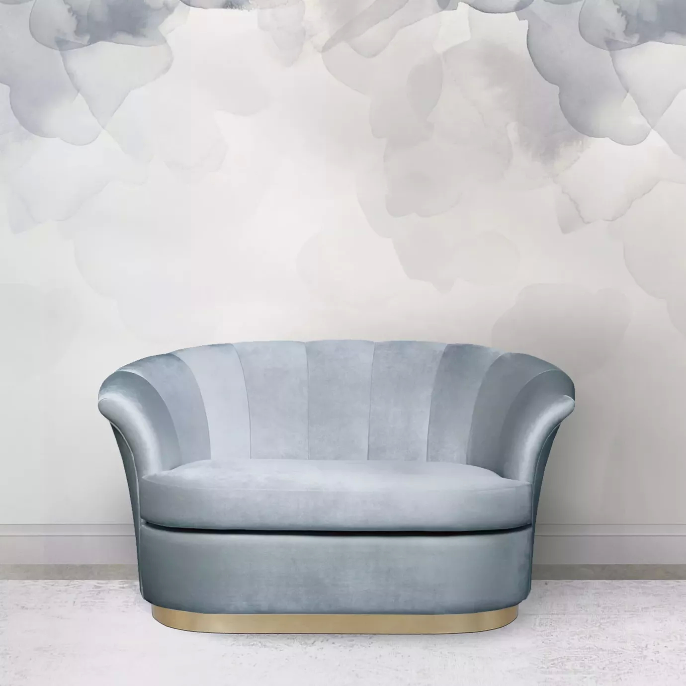 Elegant Besame Sofa with a golden metal base and light blue velvet upholstery with pleated details against a wall with a soft floral pattern in shades of blue.