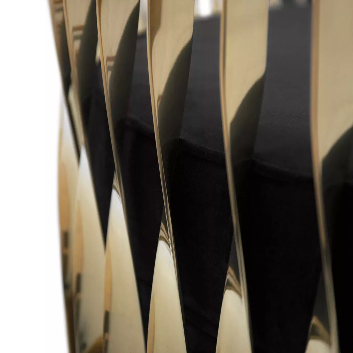 Elegant close-up of the golden metal structure with a sculptural design and the black velvet upholstery of the Mandy Sofa.