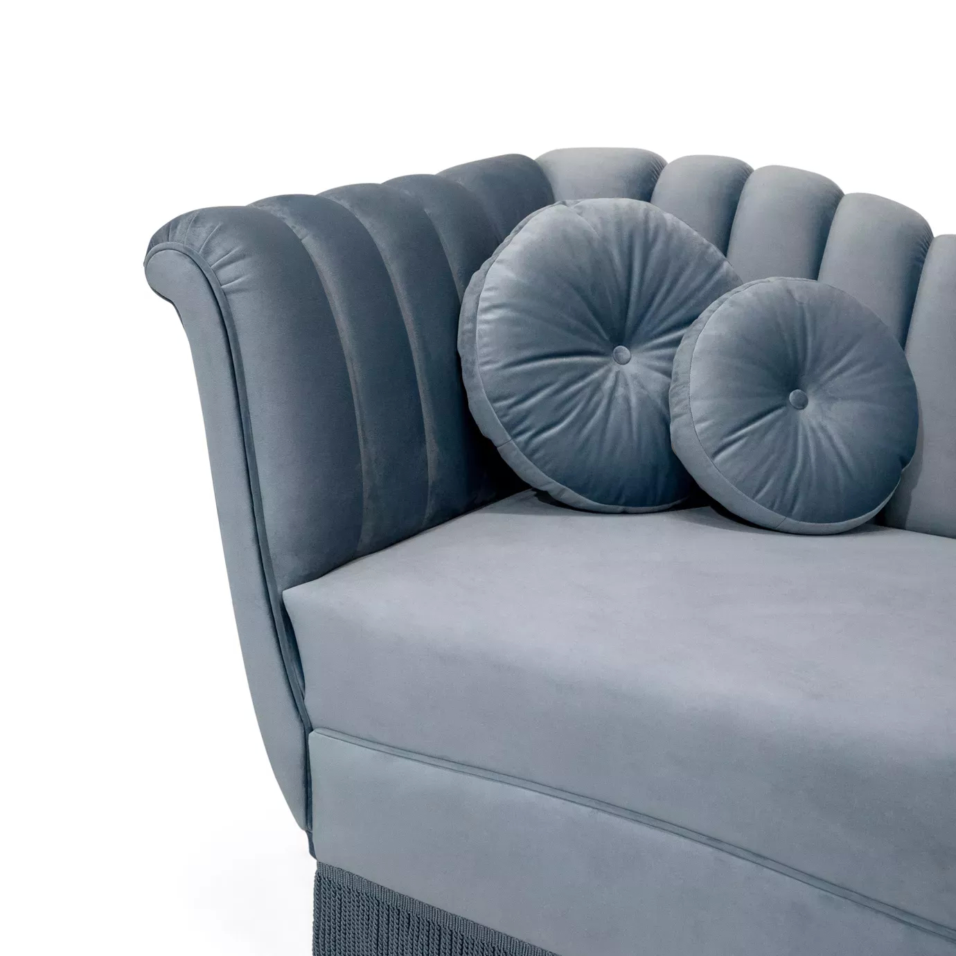 Elegant close-up of the curved arm detail, blue velvet upholstery, and round pillows of the Millicent Chaise.