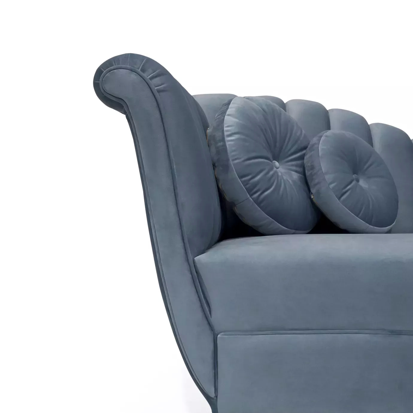 Elegant close-up of the curved arm detail, blue velvet upholstery, and round pillows of the Millicent Chaise.