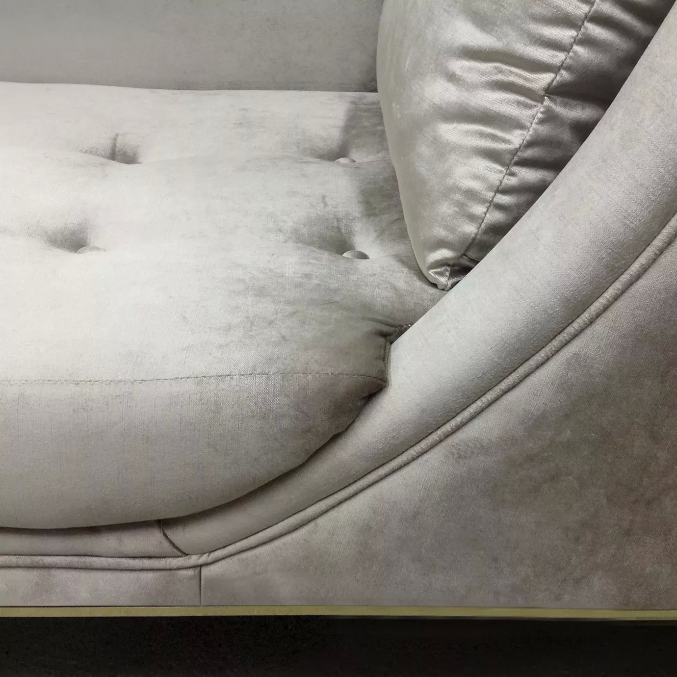 Elegant close-up of the light gray velvet upholstery with button-tufted details and pillow of the Envy Chaise.