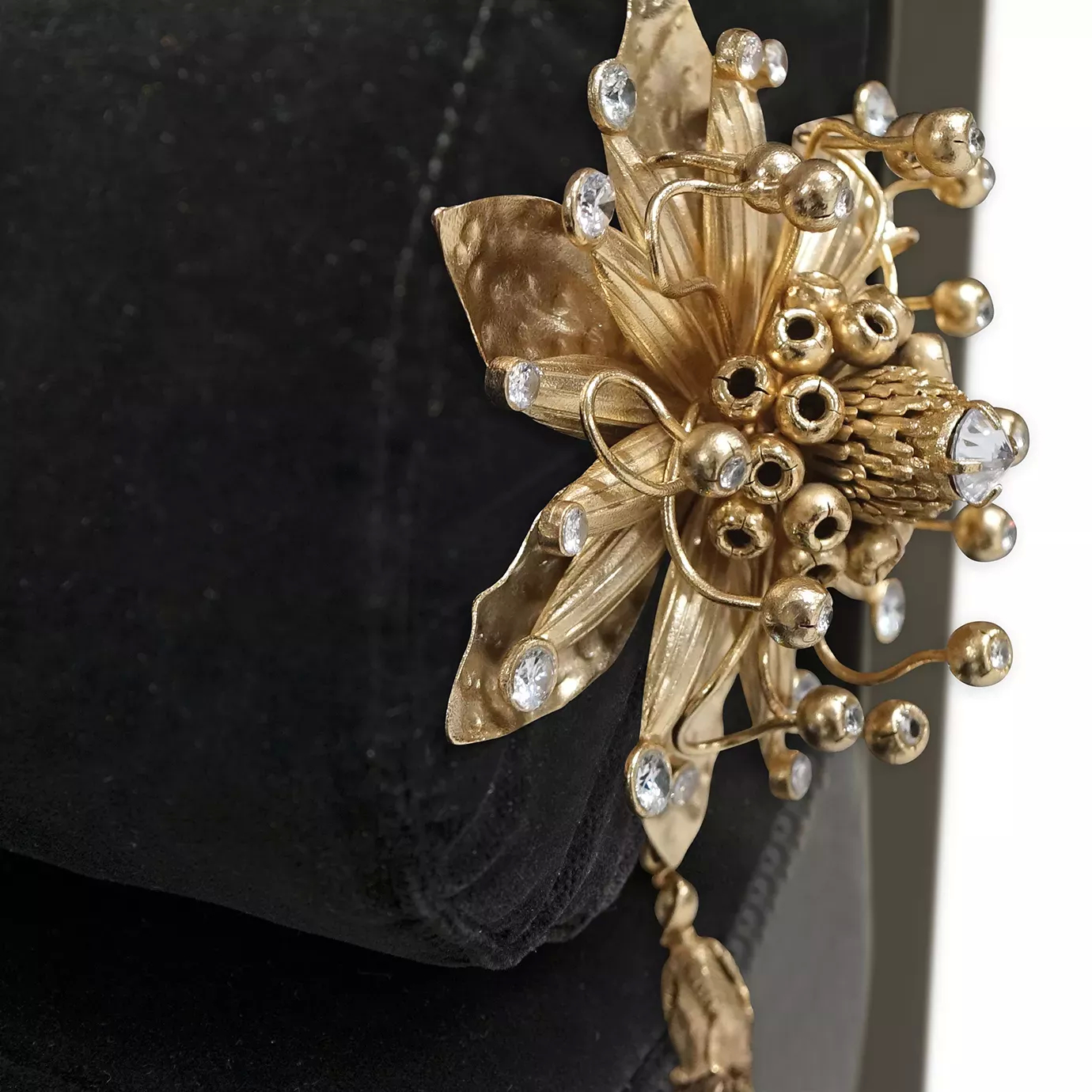 Elegant close-up of the sculptural golden detail with crystal applications and tassel of the Privê Daybed.