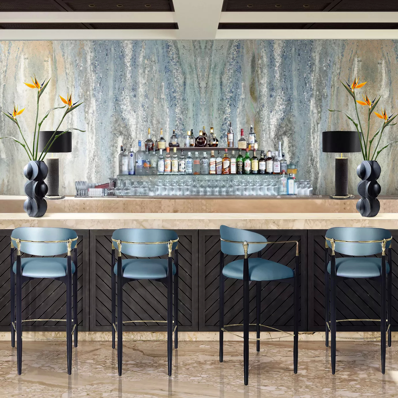 A bar counter with four bar stools in front, featuring dark blue tones and with golden details. In the background, there are drinks and two vases with flowers.