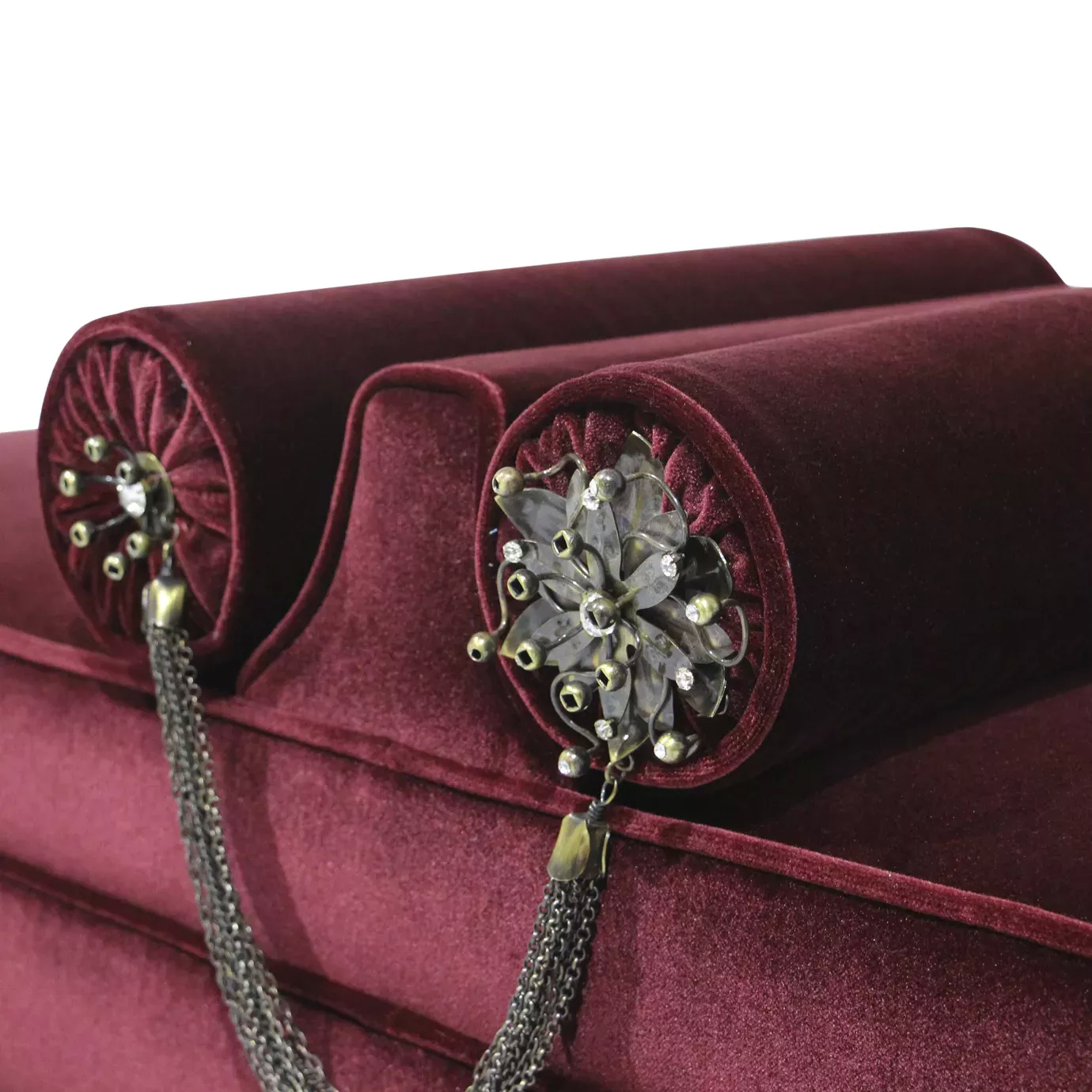 Elegant close-up of the decorative cylindrical pillows with metallic applications and chains of the Lé Lé Bench.