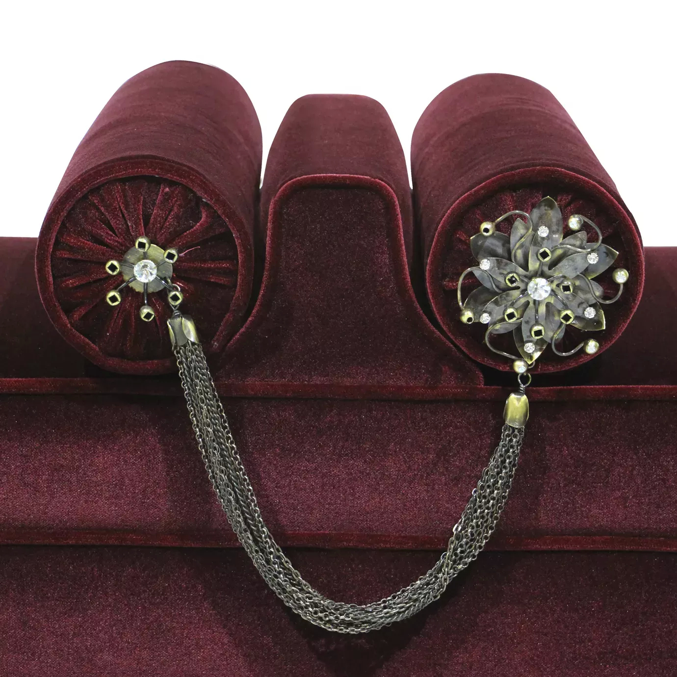 Elegant close-up of the decorative cylindrical pillows with metallic applications and chains of the Lé Lé Bench.