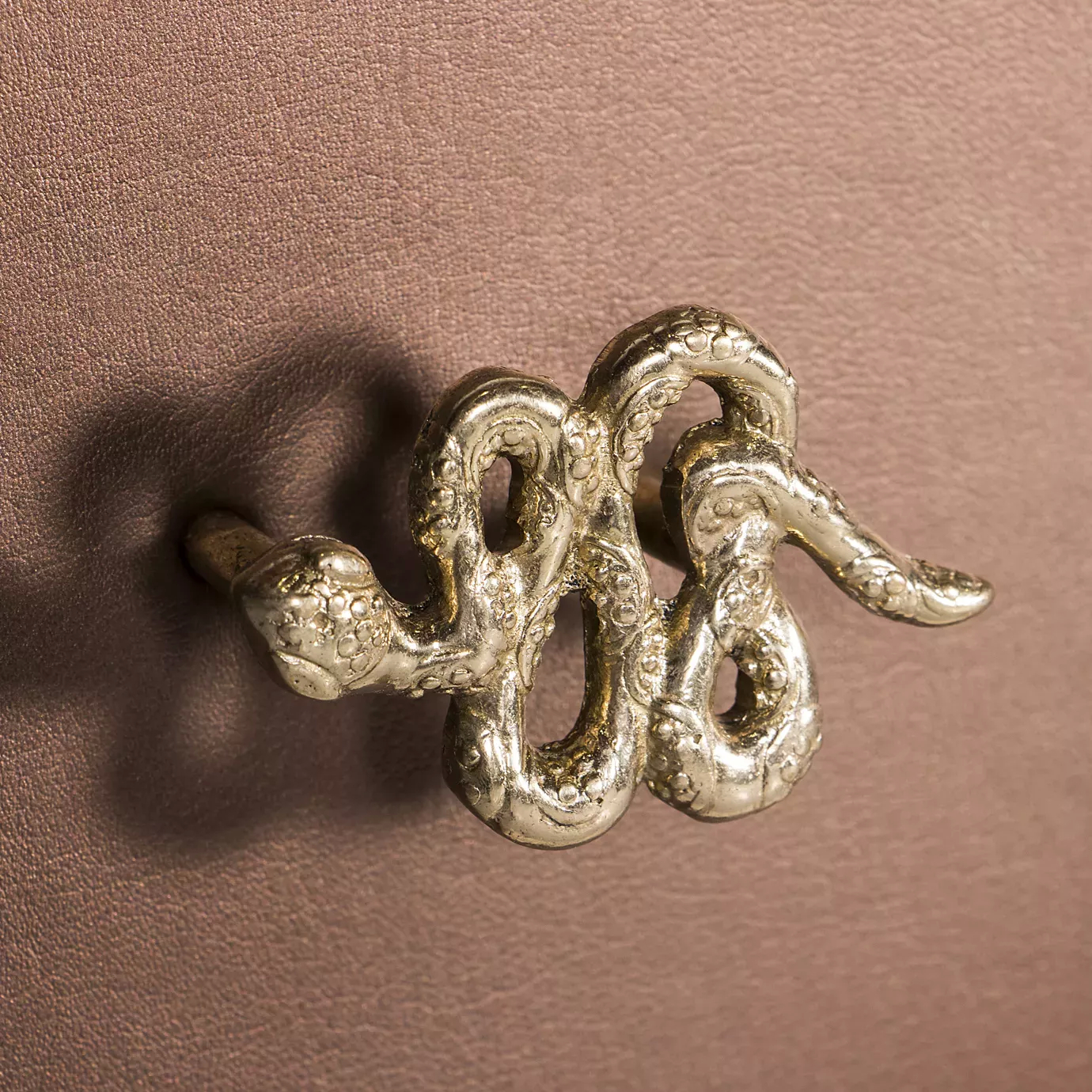 Detailed close-up of the elegant golden snake handle of the Untamed Console.