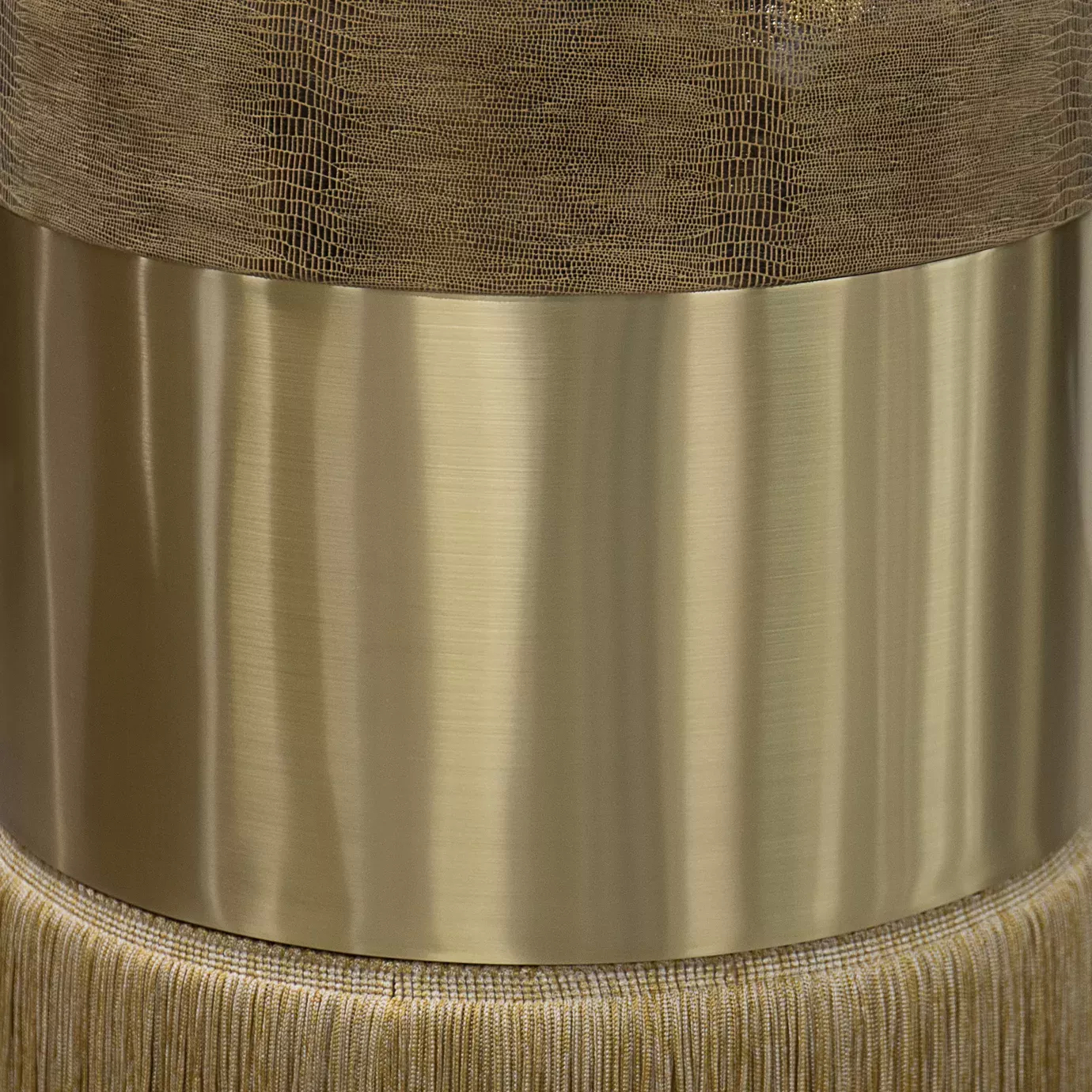 Elegant close-up of the round textured leather seat detail in golden tones and the golden band of the Olivia Stool's base.