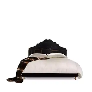 Elegant Alexia Bed with high headboard in black velvet with golden details and studs, white bedding, and a fur throw.