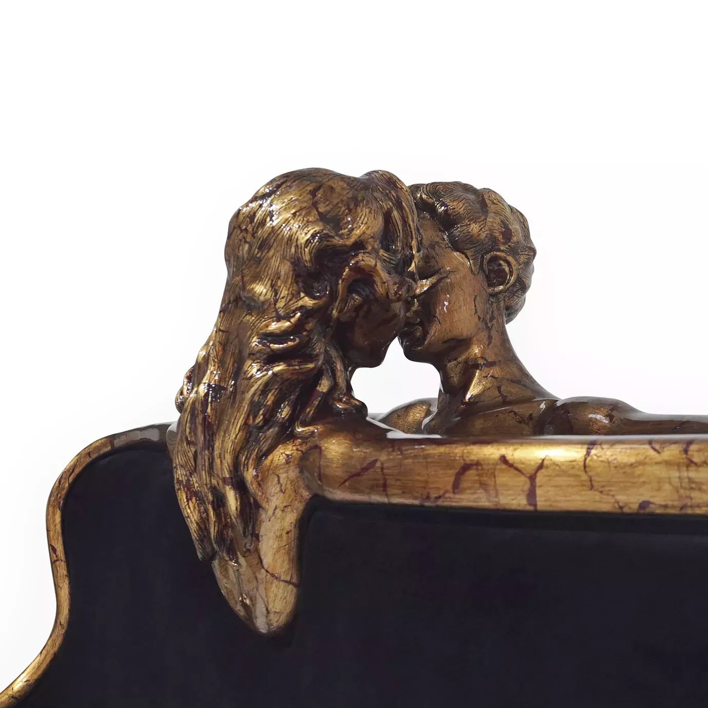 Elegant close-up of the sculptural golden detail of a kissing couple on the black velvet headboard of the Forbidden Bed.