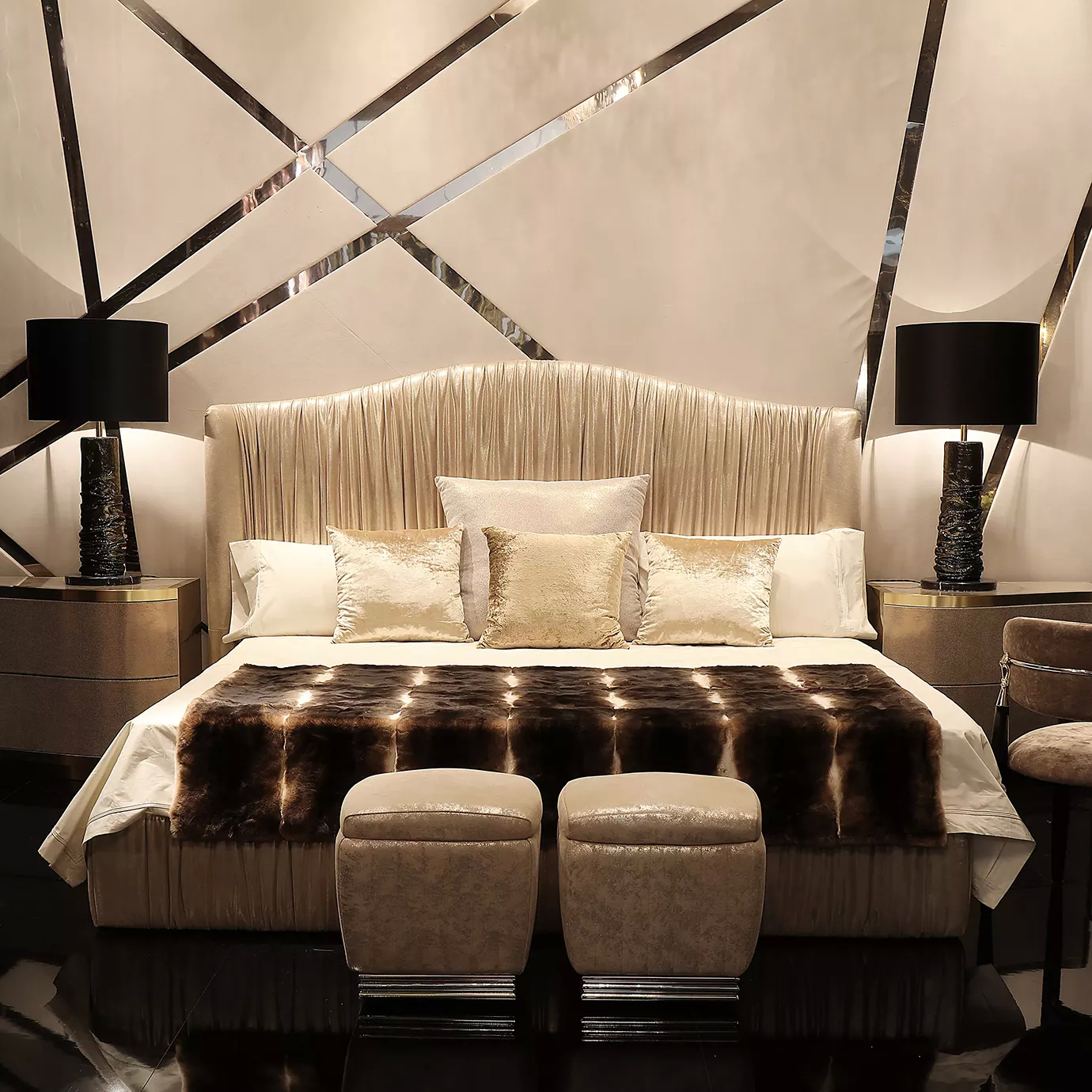 Elegant bedroom with the Plissé Bed featuring a high headboard and pleated light textured fabric upholstery, light bedding with a dark fur throw, two upholstered stools at the foot, and modern bedside tables with black lamps.