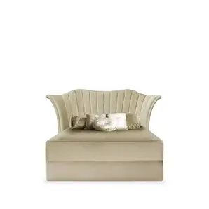 A luxurious Caprichosa Bed by Koket features a tall, scalloped headboard with vertical channel tufting in a soft, light beige velvet. Several plush pillows rest on the matching upholstered base.