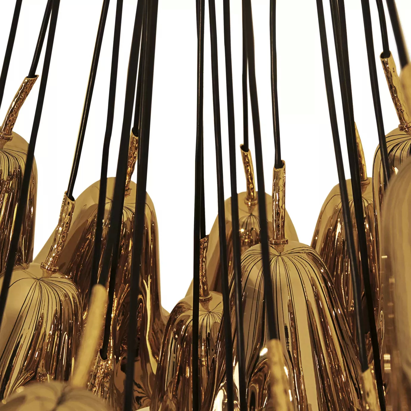Elegant close-up of the connection detail of the golden flower-shaped pieces to the black wires of the Gia Chandelier.