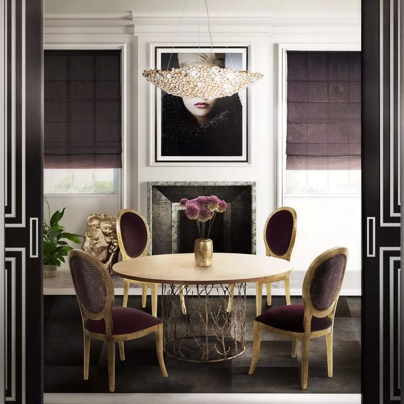 Elegant dining room with a round table featuring a light top and a sculptural golden base, wine-toned upholstered chairs with golden accents, and the Eternity Demi Lune Chandelier suspended above the table.