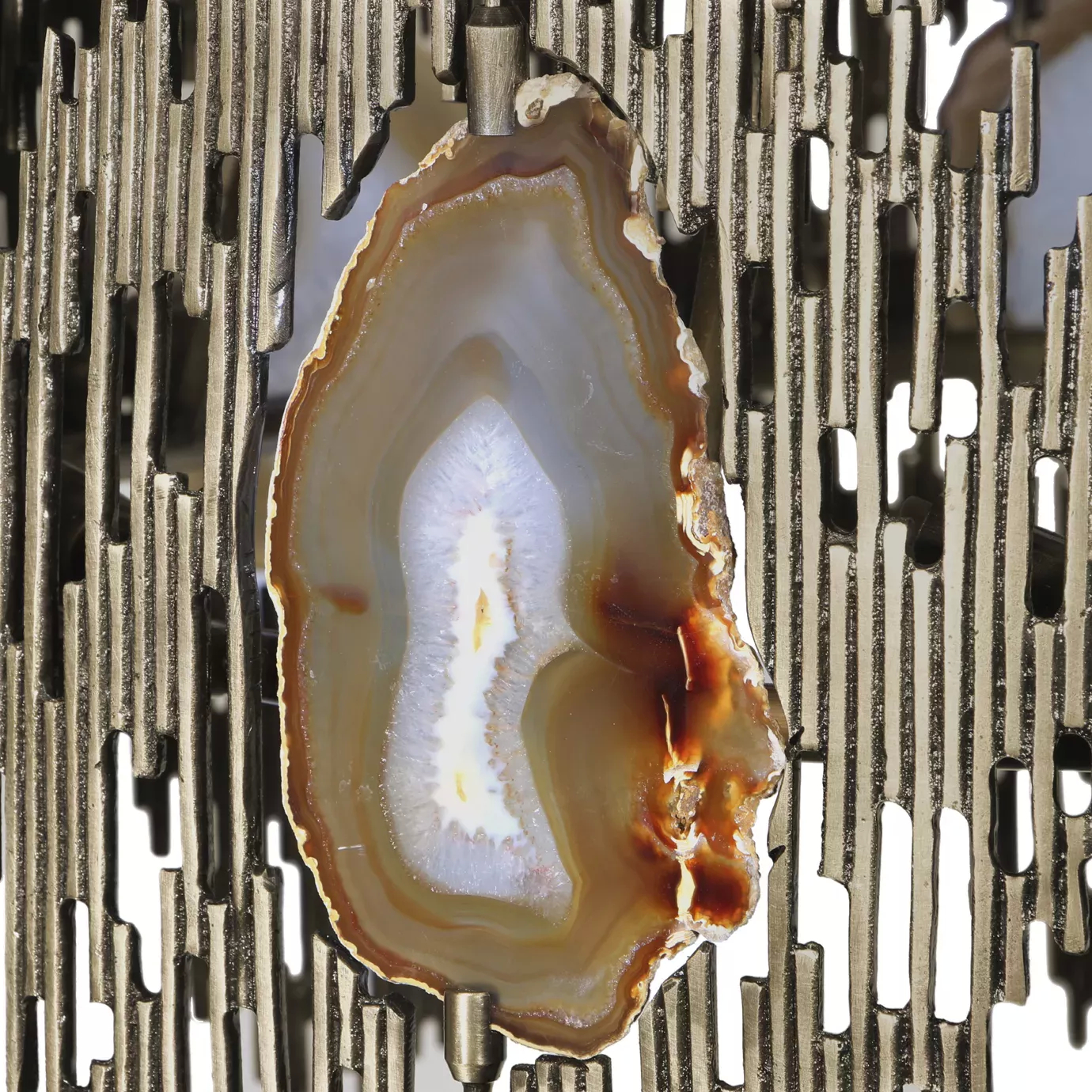 Elegant close-up of the detail of a translucent agate slice with shades of white, grey, and brown embedded in the sculptural golden frame of the Vivre Chandelier.