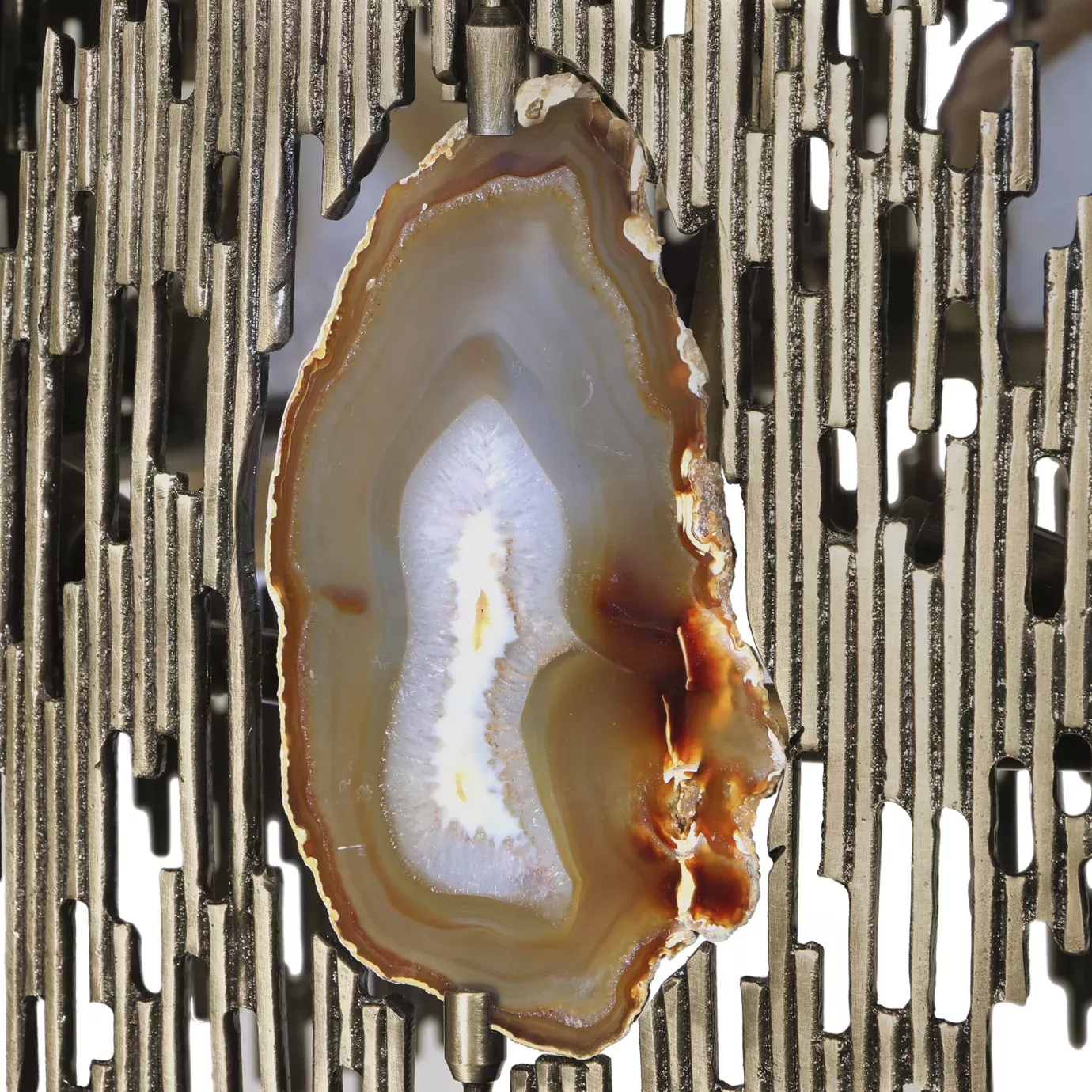 Elegant close-up of the detail of a translucent agate slice with shades of white, grey, and brown embedded in the sculptural golden frame of the Vivre Rectangular Chandelier.