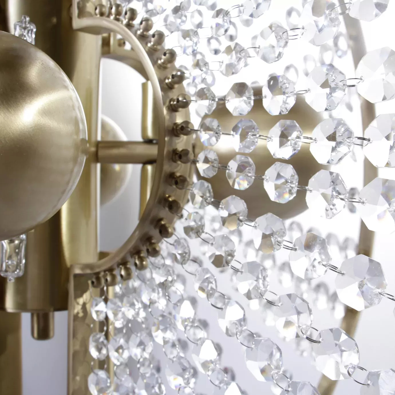 Close up of Roxy Chandelier by KOKET,  featuring crystal sunbursts and a satin brass halo