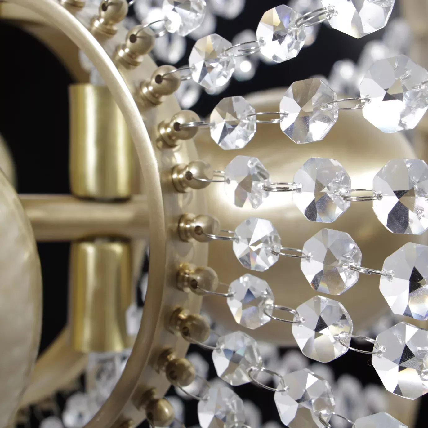 Close up of Roxy Chandelier by KOKET,  featuring crystal sunbursts and a satin brass halo
