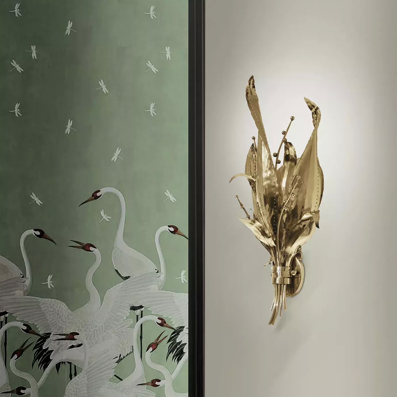 Elegant detail of a sculptural golden Botanica Sconce mounted on a light wall next to a door with wallpaper featuring white cranes and dragonflies on a soft green background.