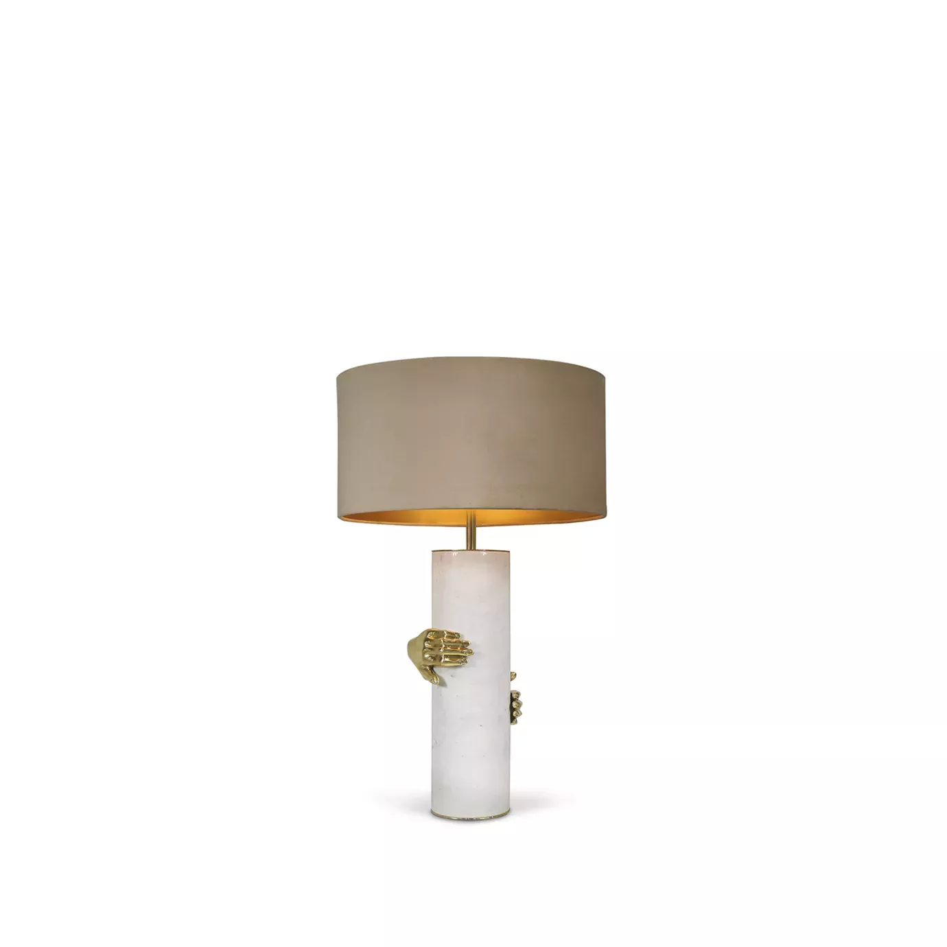 Elegant Vengeance Table Lamp with a white marble cylindrical base adorned with sculptural golden hand details gripping it, and a beige lampshade illuminated from within.