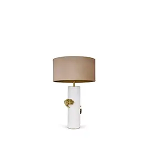 Elegant Vengeance Table Lamp with a white cylindrical base adorned with sculptural golden hand details gripping it, and a beige lampshade.