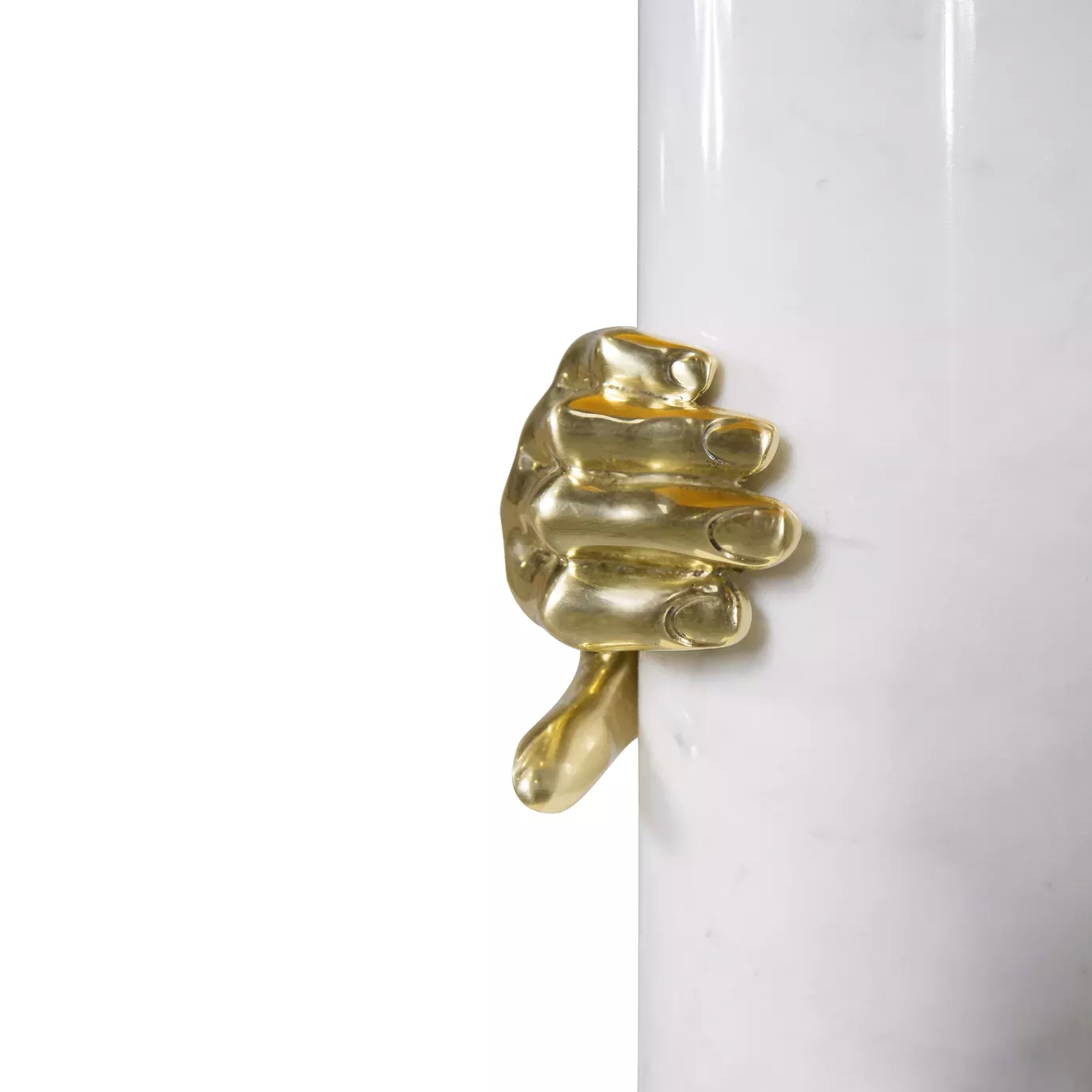 Elegant close-up of the sculptural golden hand detail gripping the white cylindrical base of the Vengeance Table Lamp.