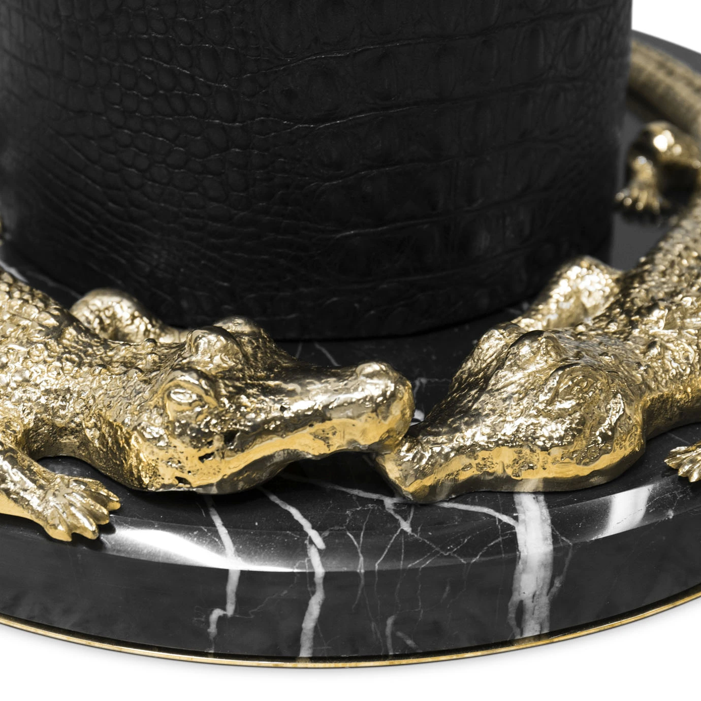 Elegant close-up of the sculptural golden crocodile details on a round black marble base with white veins, at the bottom of the Reptilian Table Lamp.