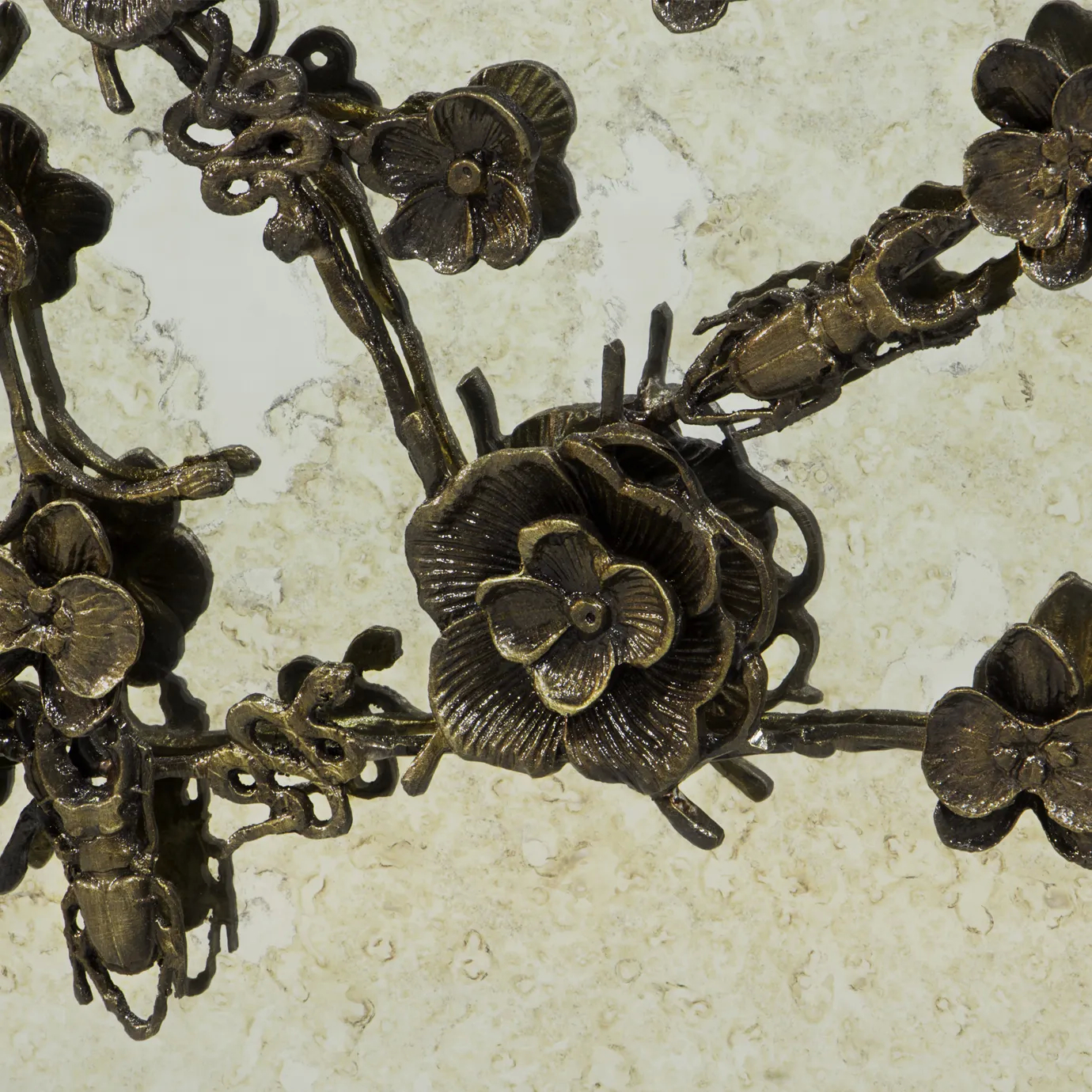 Close look on the golden floral themed ornaments present on the front doors of the Spellbound Aged Mirror Cabinet, contrasting with the light colors of the aged mirror structure.
