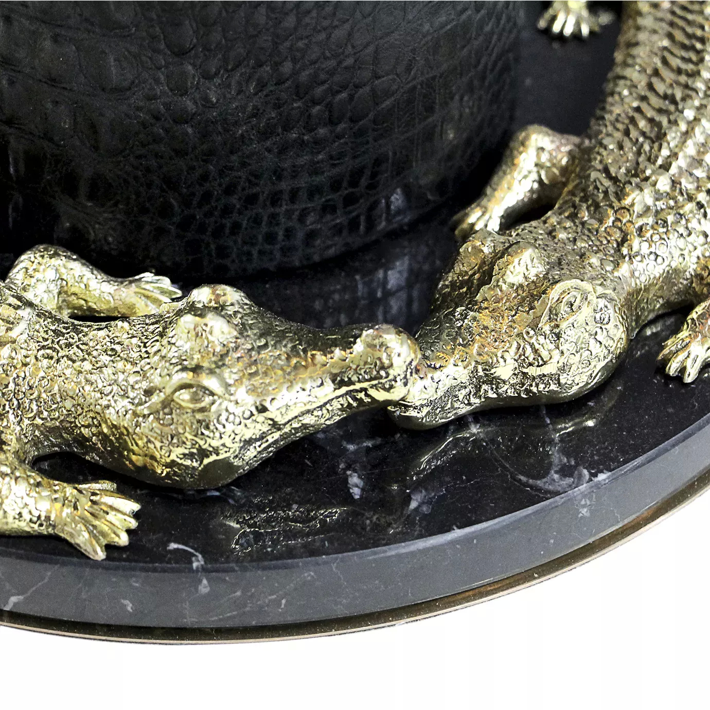 Elegant close-up of the sculptural golden crocodile details on a round black marble base with white veins, at the bottom of the Reptilian Floor Lamp.