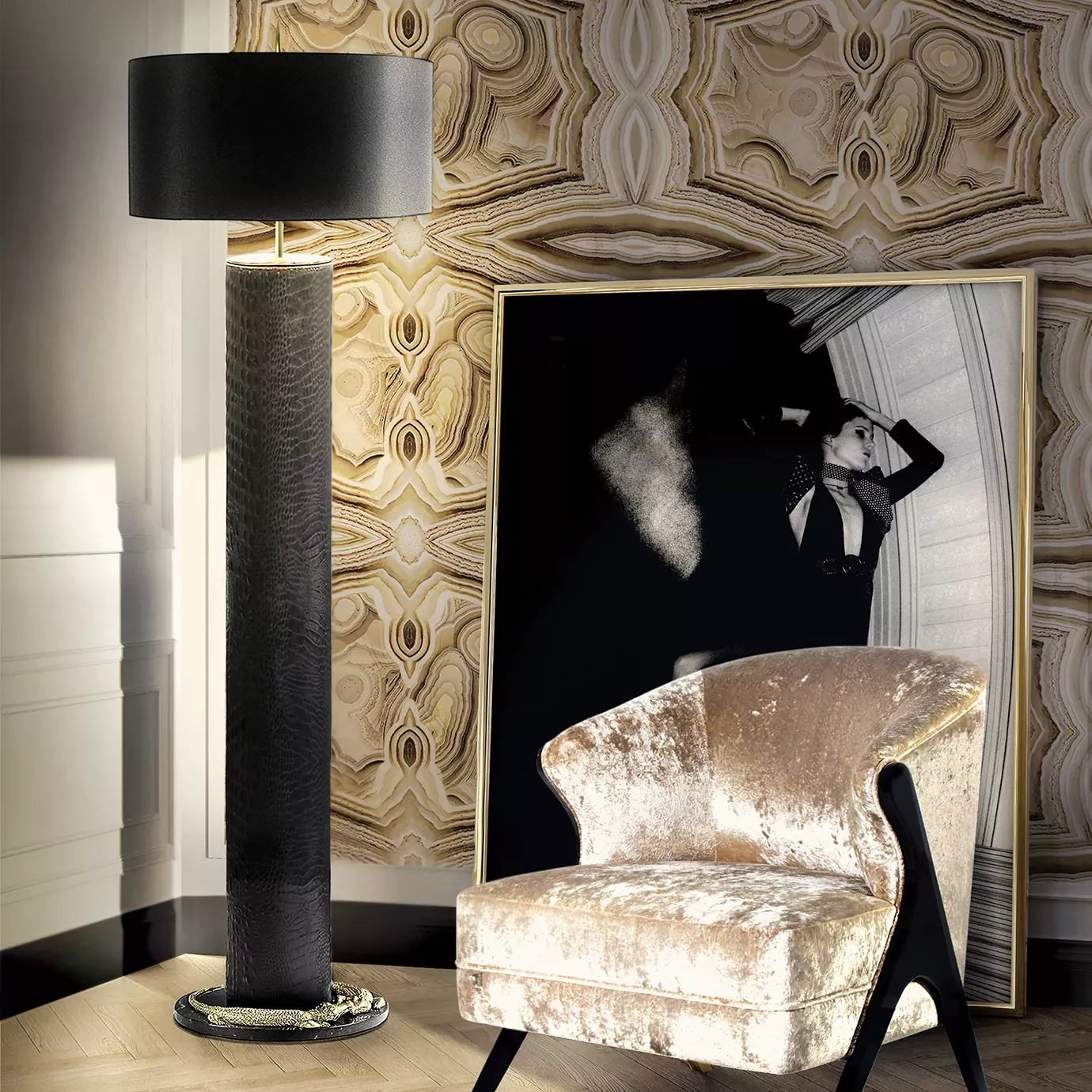 Elegant reading corner with the Reptilian Floor Lamp featuring a textured black cylindrical base and golden crocodile details, and the Armchair upholstered in beige velvet with glossy black wood accents, next to a large black and gold framed photograph, on a light wooden floor and against a wall with beige and brown-toned textured wallpaper.