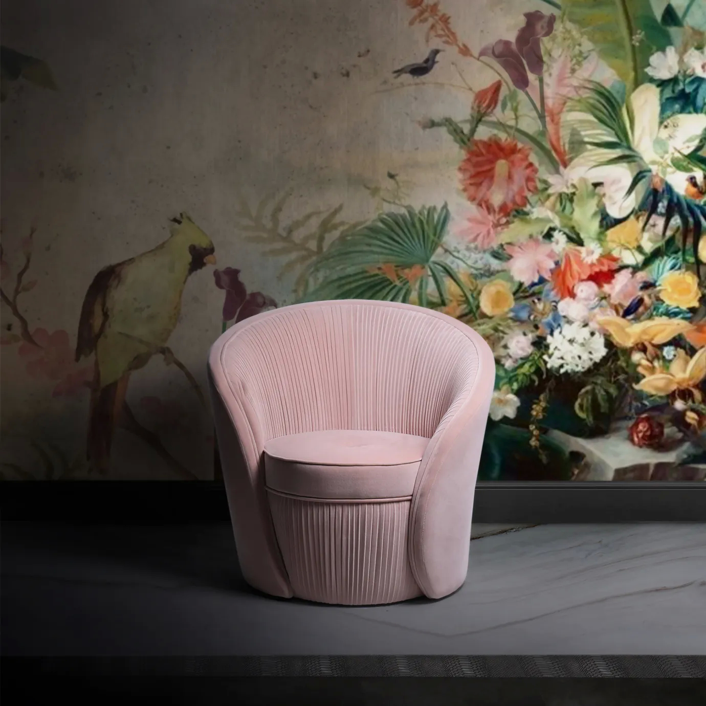 Elegant corner with the Bloom Armchair upholstered in soft pink fabric with a rounded design and vertical pleated details on the base and backrest, on a dark floor and against a wall with an artistic floral and bird mural in soft tones.